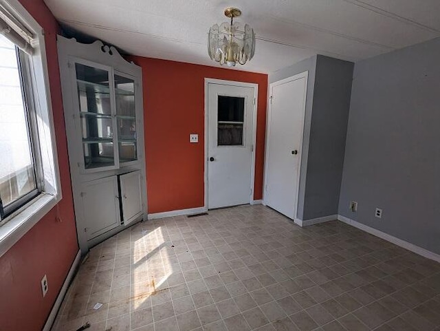 interior space with plenty of natural light, baseboards, and an inviting chandelier