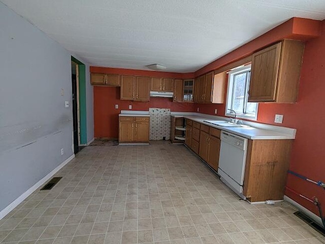 kitchen with brown cabinetry, dishwasher, under cabinet range hood, and a sink