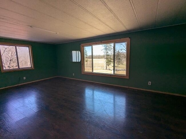unfurnished room with baseboards and dark wood-style floors