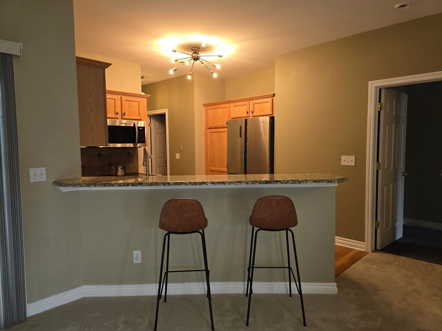 45645 Graystone Ln, Canton, MI 48187 - kitchen with appliances with stainless steel finishes, a peninsula, a breakfast bar, carpet flooring, and baseboards
