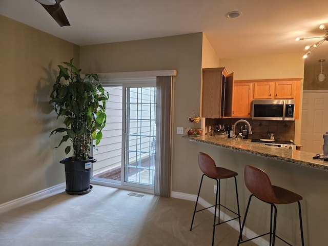 45645 Graystone Ln, Canton, MI 48187 - kitchen with stainless steel microwave, a ceiling fan, baseboards, stone countertops, and carpet floors