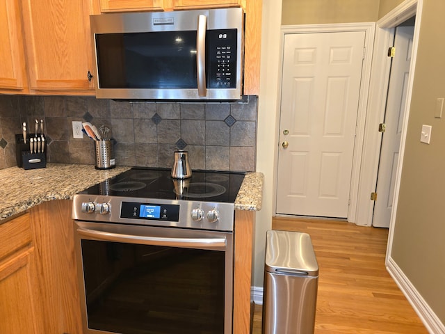 45645 Graystone Ln, Canton, MI 48187 - kitchen featuring appliances with stainless steel finishes, light wood finished floors, backsplash, light stone countertops, and baseboards