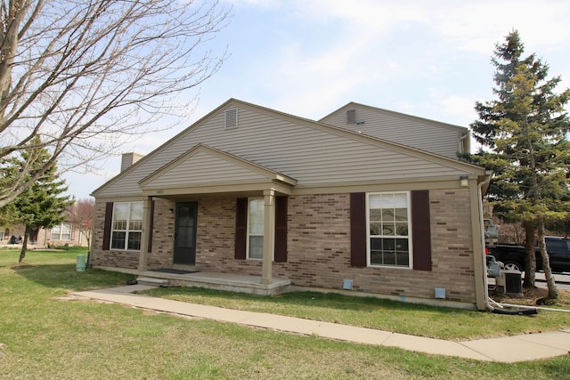 view of front of property featuring a porch, a front lawn, brick siding, and a chimney