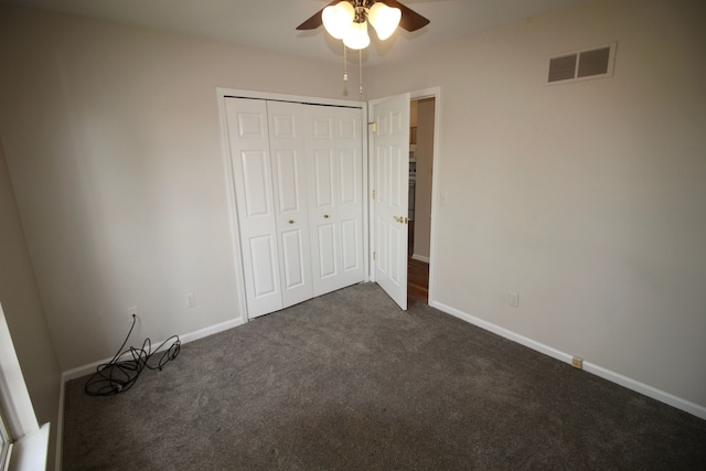 unfurnished bedroom with dark colored carpet, baseboards, visible vents, a ceiling fan, and a closet