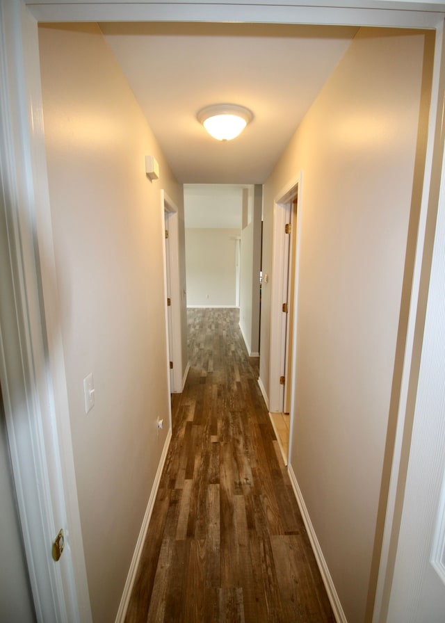 hallway with baseboards and dark wood-type flooring