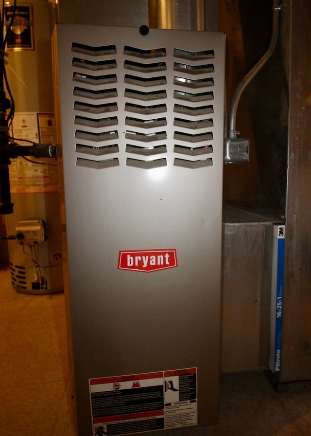 utility room featuring heating unit and gas water heater