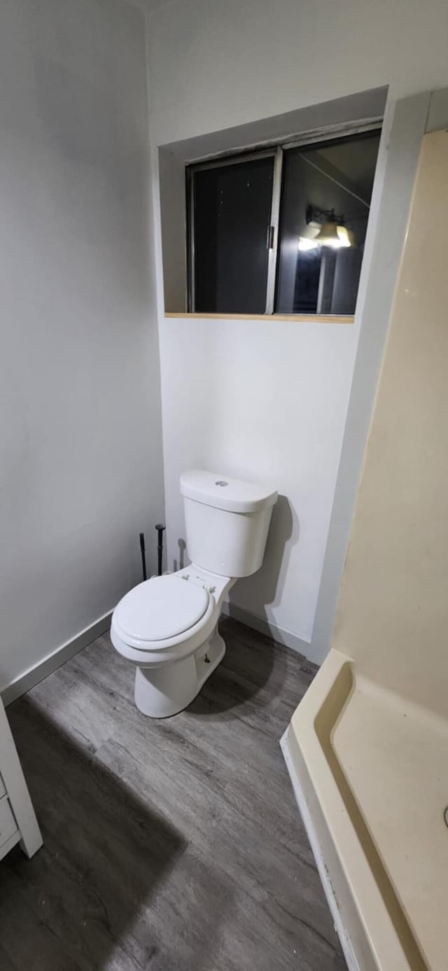 full bathroom featuring toilet, wood finished floors, a shower, and baseboards