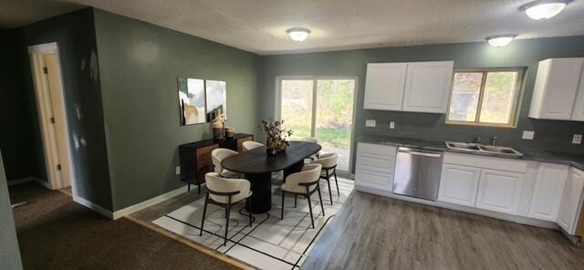 9864 Cadillac Dr, Lake, MI 48632 - kitchen with dishwasher, a sink, white cabinetry, light wood-style flooring, and dark countertops