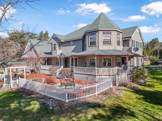 victorian house with covered porch, a front lawn, and fence