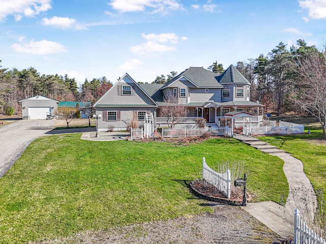 victorian house with a front lawn, aphalt driveway, an outbuilding, and a garage