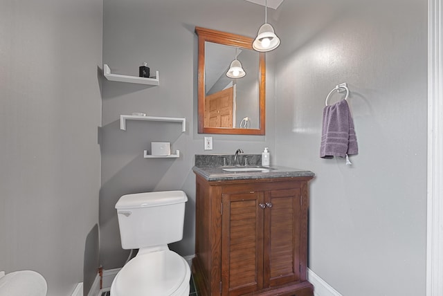 bathroom featuring toilet, vanity, and baseboards