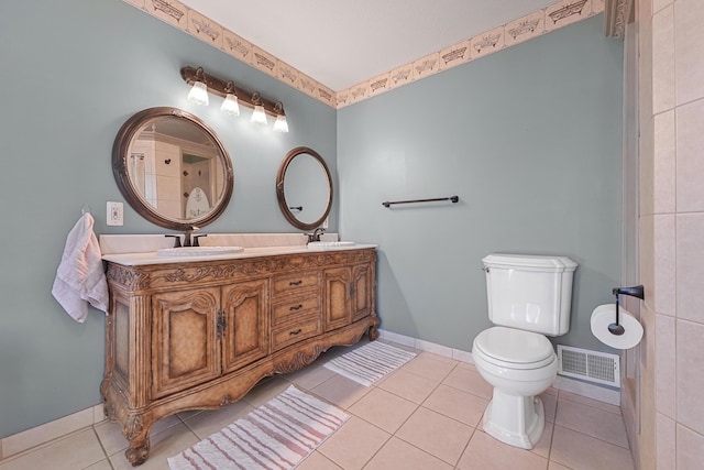 bathroom featuring double vanity, toilet, a sink, baseboards, and visible vents