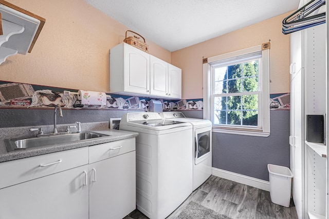 washroom featuring independent washer and dryer, light wood-style flooring, a sink, baseboards, and cabinet space