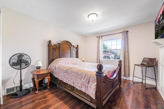 bedroom featuring hardwood / wood-style floors, visible vents, a textured ceiling, and baseboards