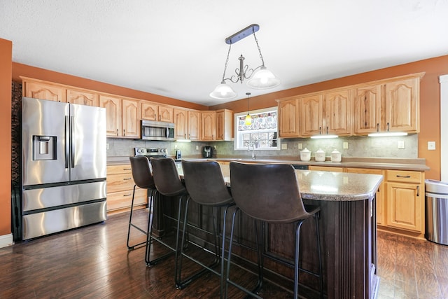 kitchen featuring dark wood-style floors, light brown cabinetry, appliances with stainless steel finishes, and a kitchen island