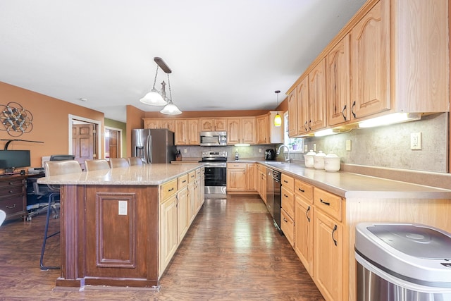 kitchen featuring a kitchen breakfast bar, a sink, appliances with stainless steel finishes, and dark wood finished floors