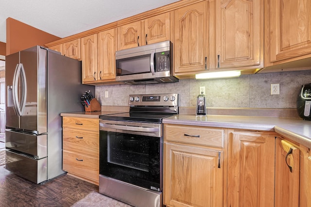 kitchen featuring dark wood finished floors, decorative backsplash, appliances with stainless steel finishes, and light countertops