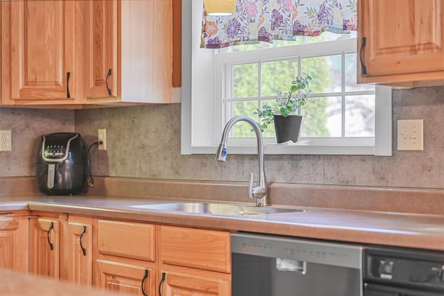 kitchen featuring decorative backsplash, dishwasher, light countertops, and a sink