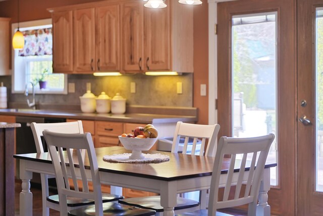 kitchen featuring a sink, light brown cabinetry, pendant lighting, light countertops, and backsplash