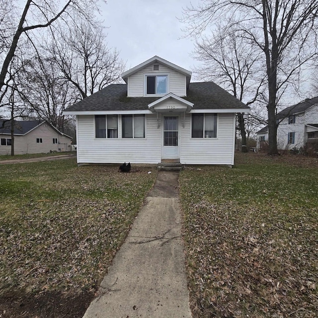 bungalow-style home featuring a front lawn and roof with shingles