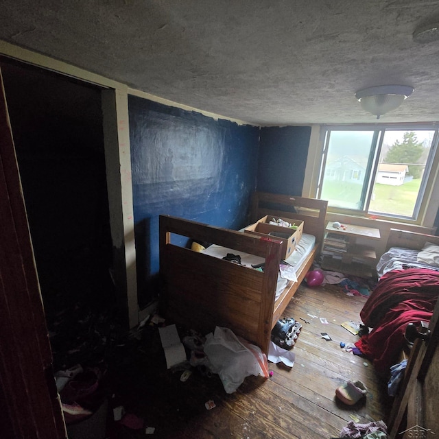 bedroom with a textured ceiling and wood-type flooring