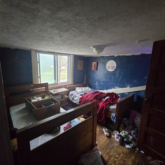 bedroom with a textured ceiling and hardwood / wood-style flooring
