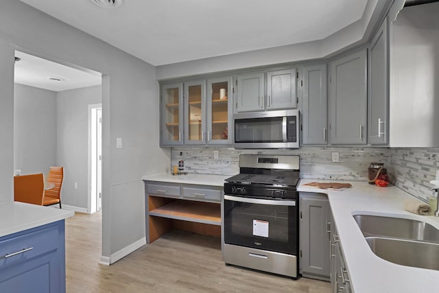 kitchen with stainless steel appliances, gray cabinets, decorative backsplash, and light countertops