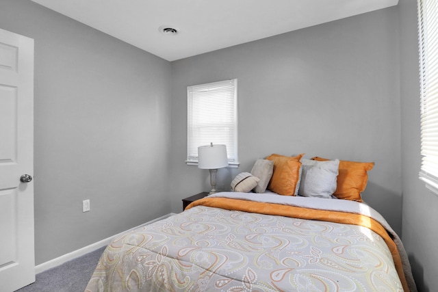 bedroom with carpet, multiple windows, and baseboards