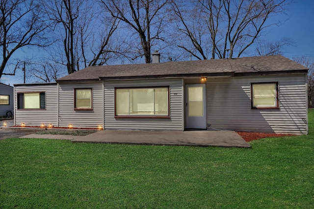 rear view of property featuring a yard, a patio area, and roof with shingles