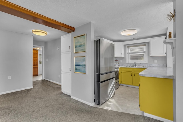 8033 S Portage Rd, Jackson, MI 49201 - kitchen featuring a textured ceiling, stainless steel appliances, light countertops, light colored carpet, and white cabinetry