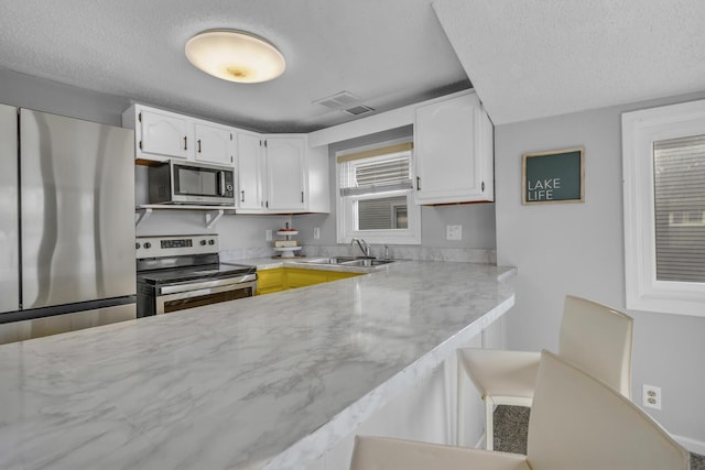 8033 S Portage Rd, Jackson, MI 49201 - kitchen featuring white cabinets, stainless steel appliances, a textured ceiling, and a sink
