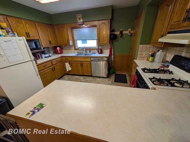 kitchen featuring under cabinet range hood, gas range, stainless steel dishwasher, light countertops, and a sink