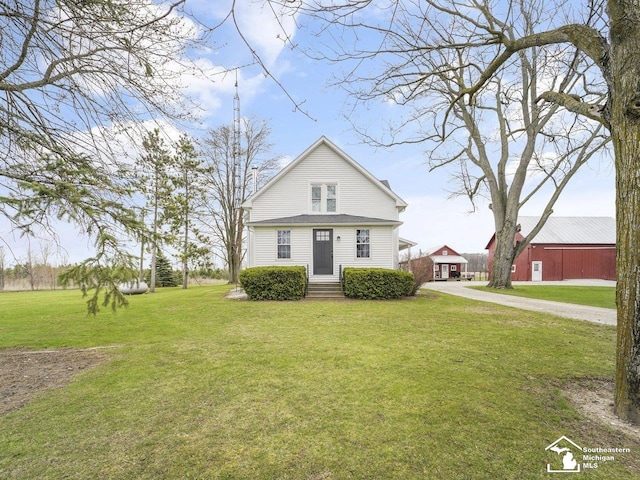 view of front of house featuring an outbuilding, a front lawn, and driveway