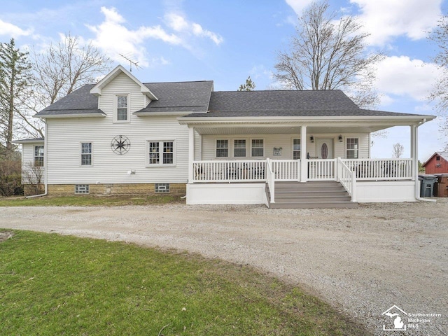 view of front of home featuring covered porch, dirt driveway, a shingled roof, and a front lawn