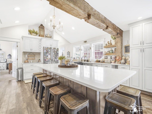 kitchen with high quality fridge, light countertops, light wood finished floors, and a notable chandelier