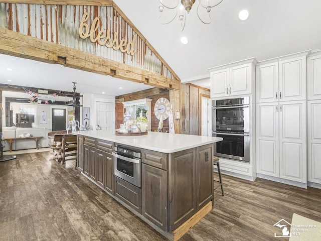 kitchen with white cabinetry, a chandelier, dark brown cabinetry, dark wood-style flooring, and stainless steel double oven