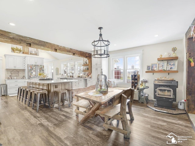 dining room with light wood-type flooring, plenty of natural light, a wood stove, and recessed lighting