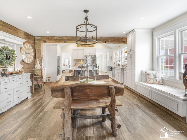 dining area with beam ceiling, recessed lighting, a chandelier, and light wood-style flooring
