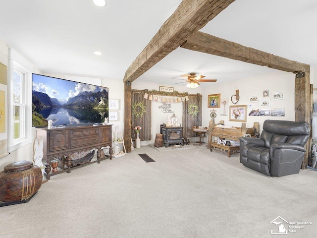 living area featuring recessed lighting, beamed ceiling, ceiling fan, carpet flooring, and a wood stove