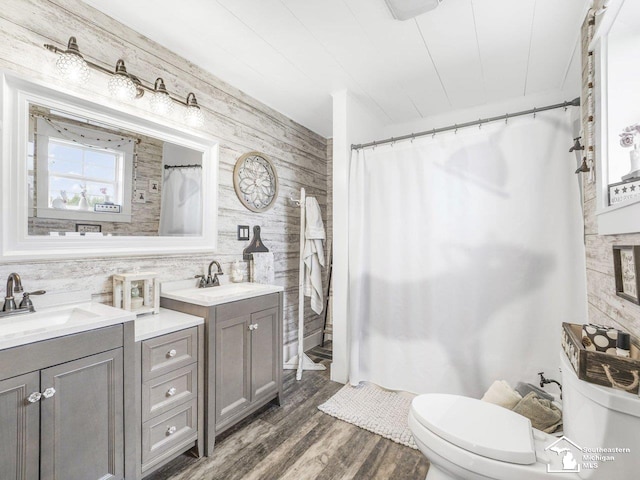 bathroom with wood finished floors, a shower with curtain, wood walls, toilet, and vanity