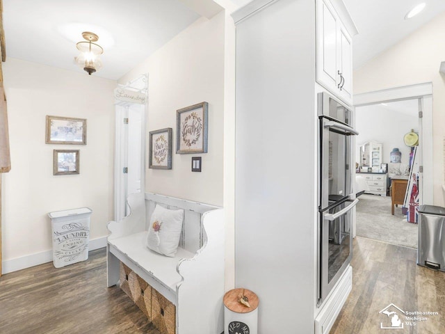 corridor with baseboards, wood finished floors, and lofted ceiling