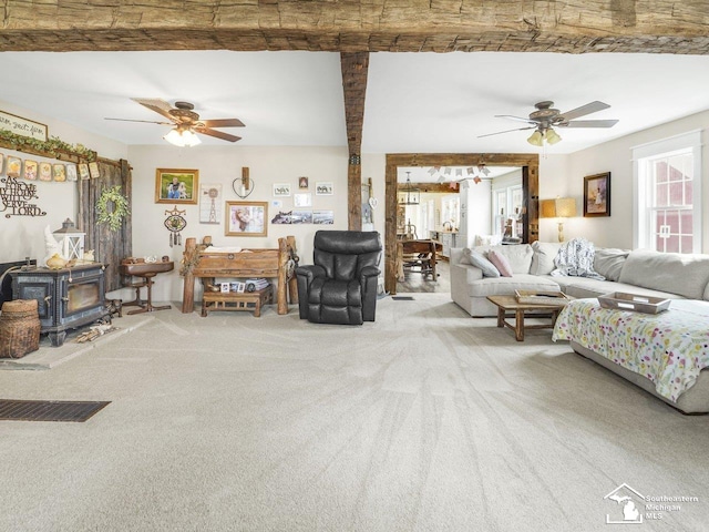 living area with carpet, ceiling fan, and a wood stove
