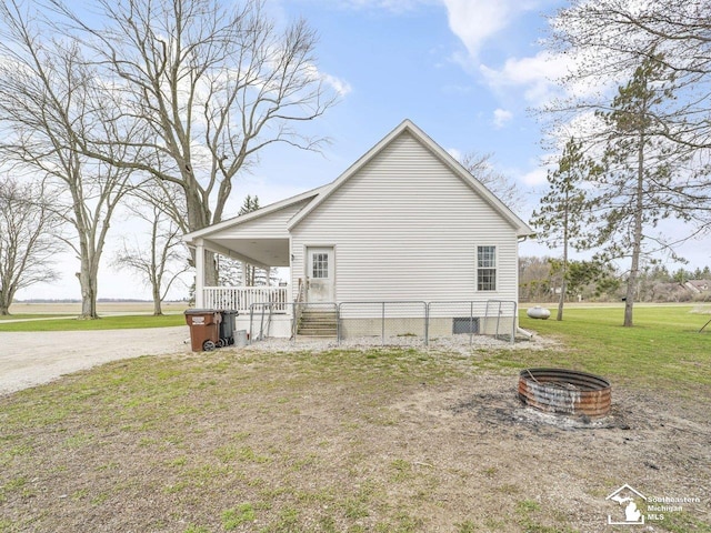view of side of property with a fire pit, a yard, and a porch