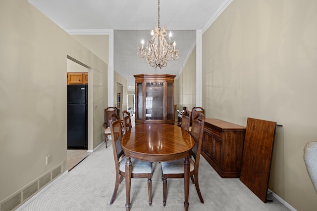 dining area with light colored carpet, visible vents, a notable chandelier, and baseboards