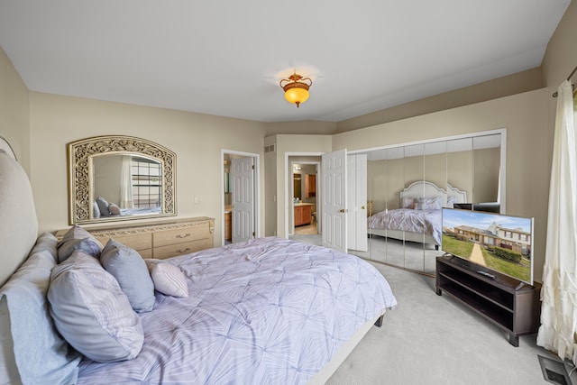 bedroom featuring ensuite bathroom, a closet, and light carpet
