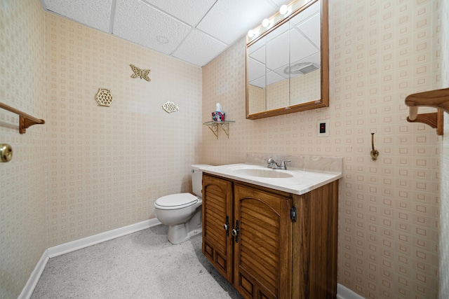 bathroom with toilet, a drop ceiling, vanity, and baseboards