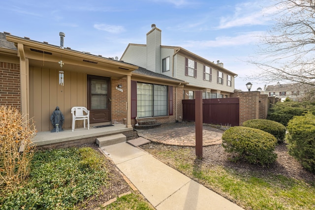 view of front of property with fence, a patio, and brick siding