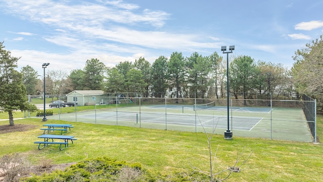 view of tennis court with fence and a yard