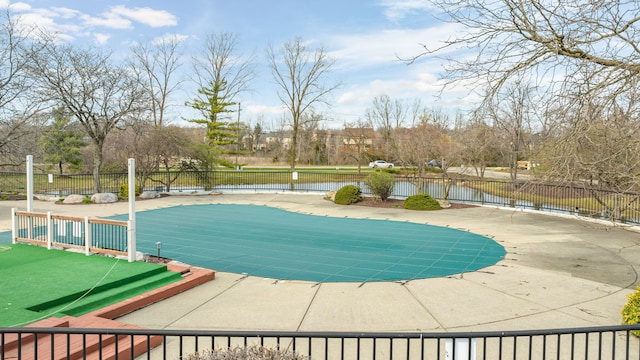 view of pool with fence, a water view, a fenced in pool, and a patio area