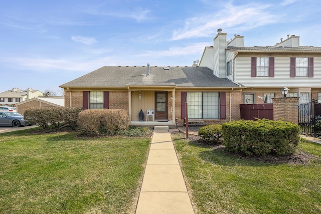 view of front of house featuring a chimney, brick siding, fence, and a front lawn